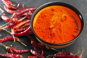 Chili powder and dried peppers on table background.